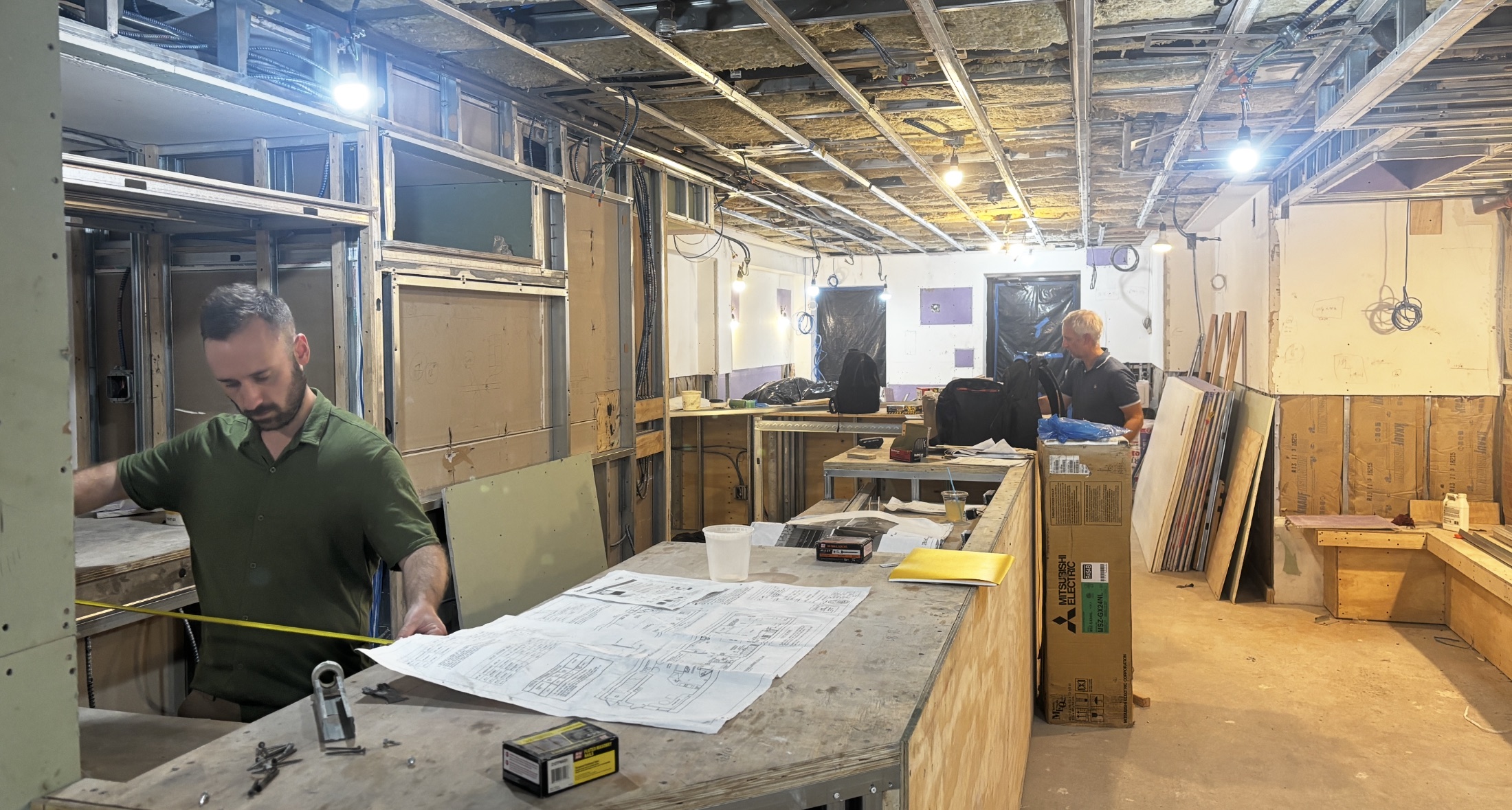 Coen measuring the Solid State Midtown build-out against the floor plans